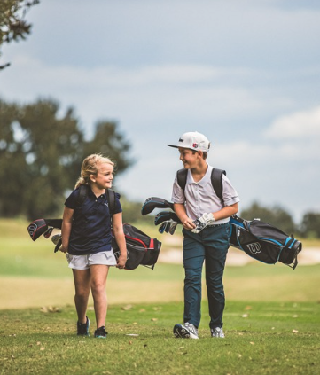 a boy and girl walking on a golf course