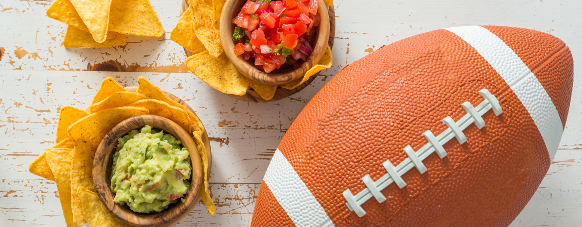 a bowl of salsa and chips next to a football