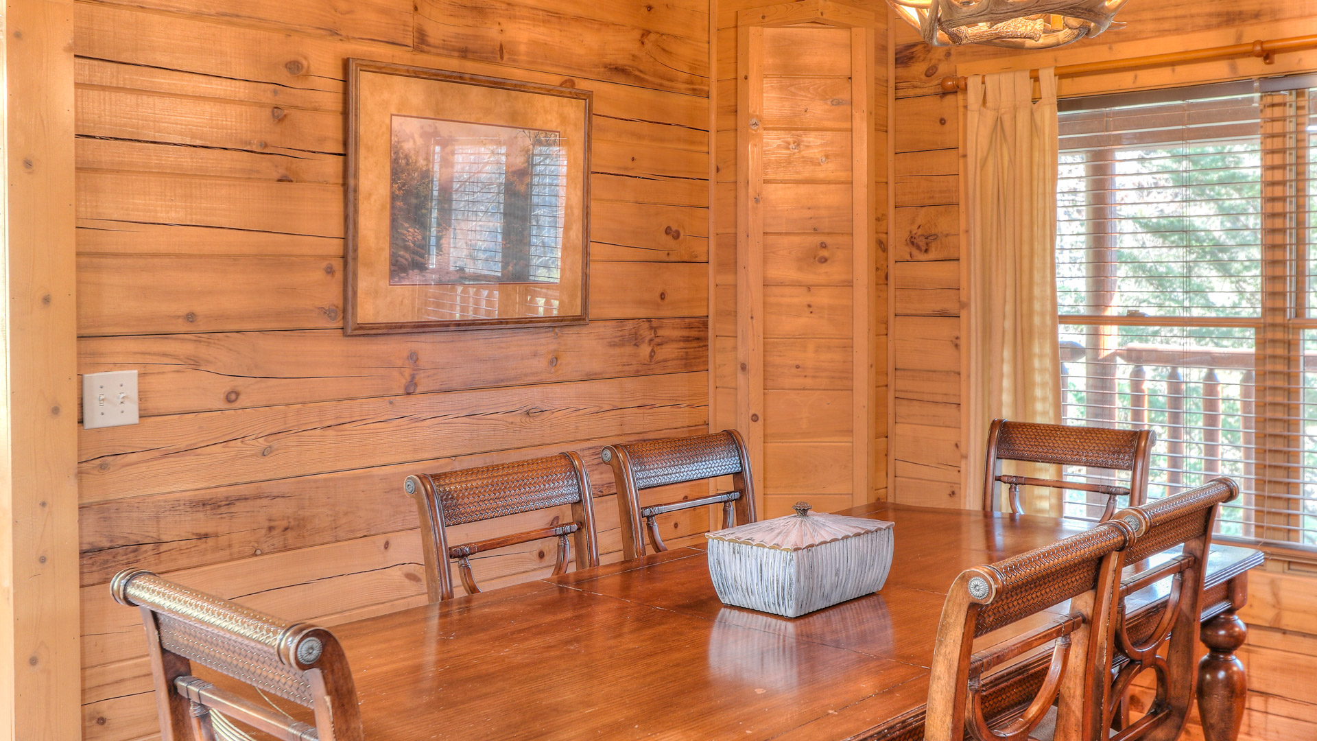 a wooden dining table with chairs in a room with a mirror