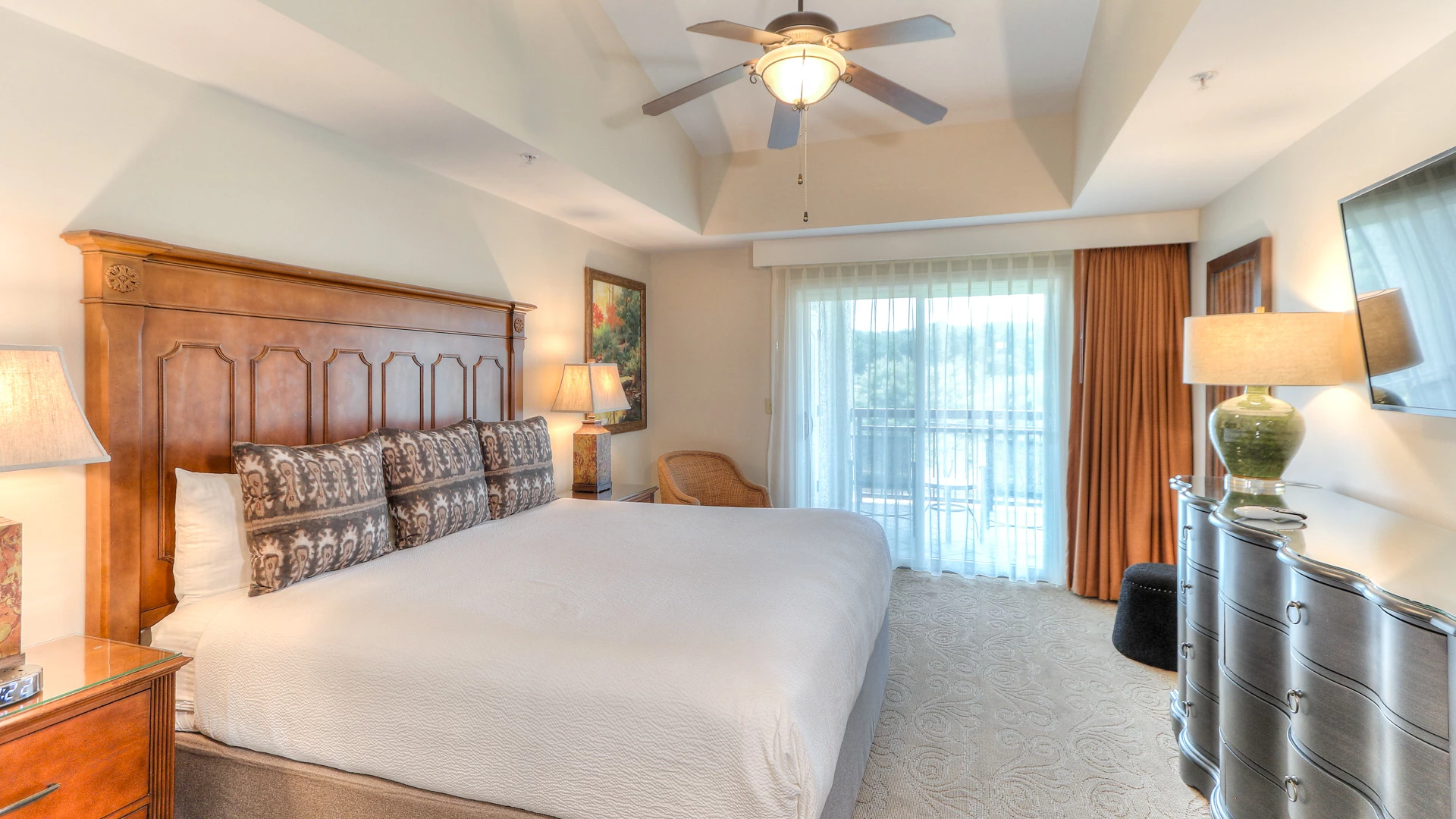 A wide view of a guest room with a large bed, dresser, and window