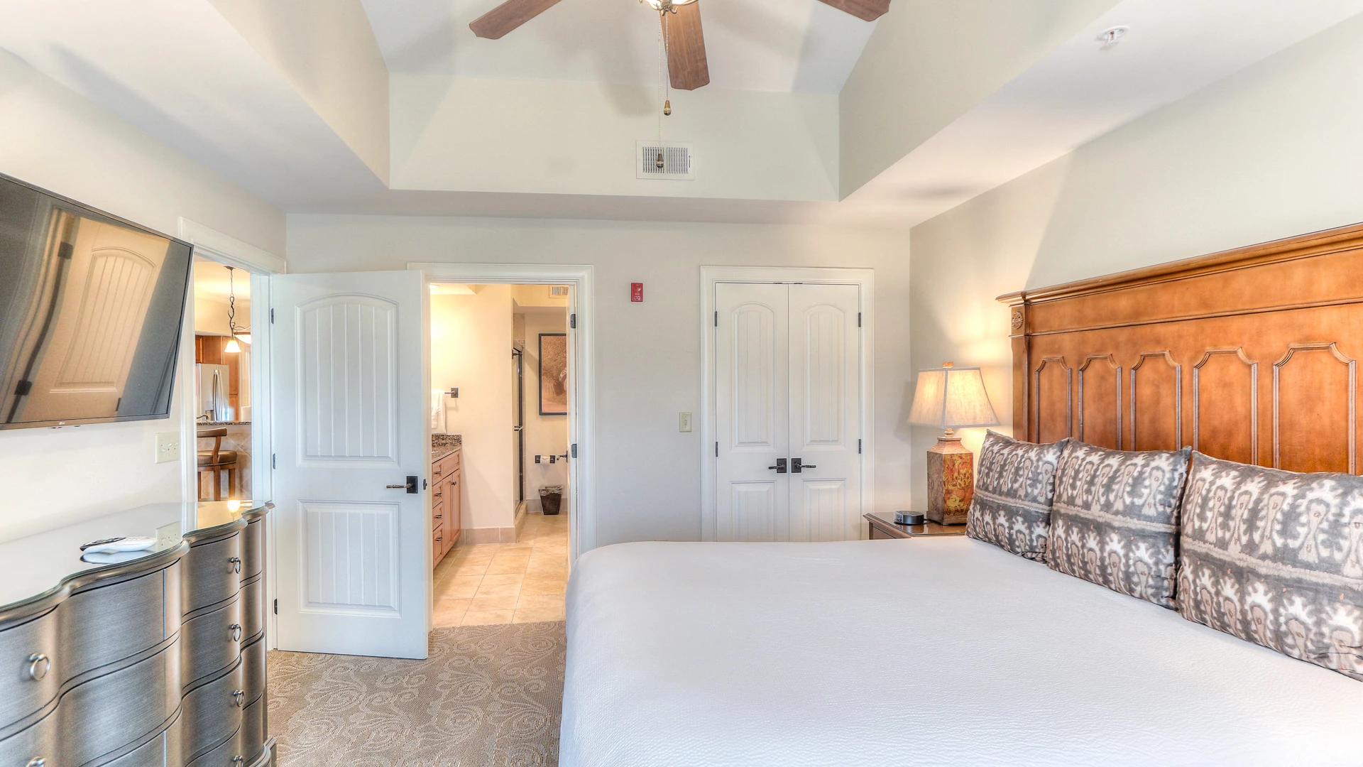 A wide view of a hotel room with a large bed, dresser, and TV on the wall.