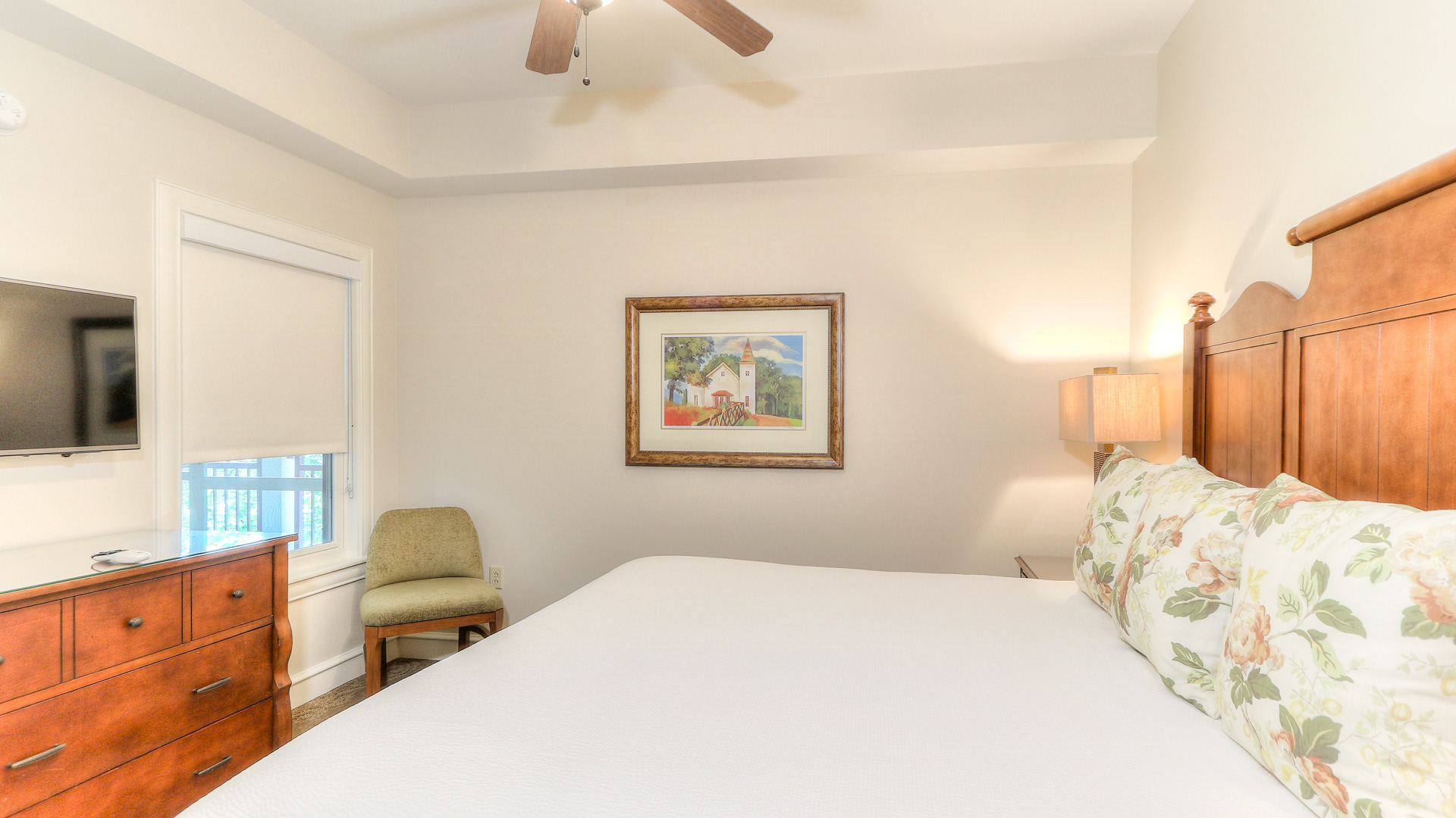 a bed with a fan and a picture on the wall