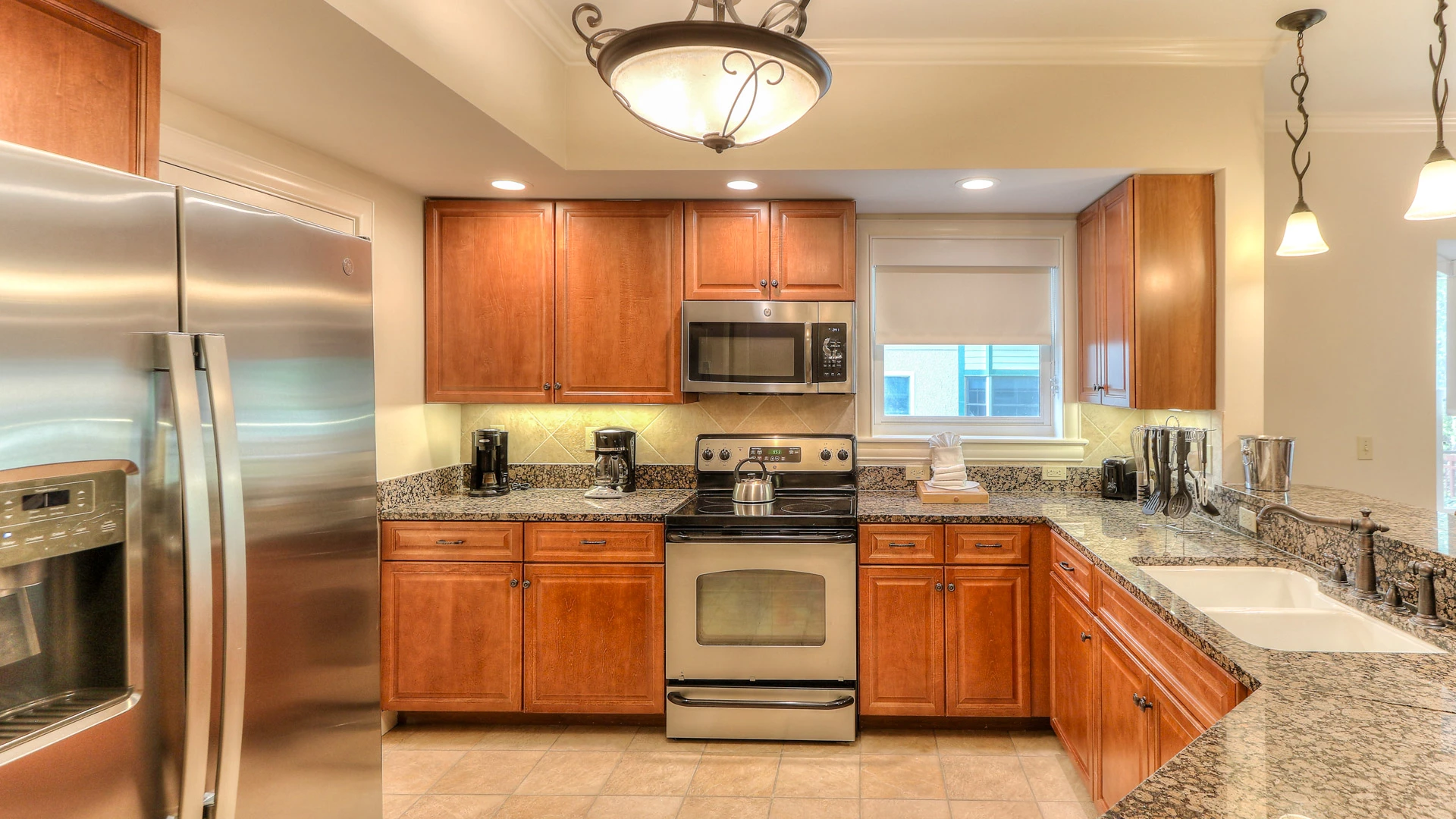 A fully equipped kitchen with stainless steel appliances, granite countertops, and wood cabinets.