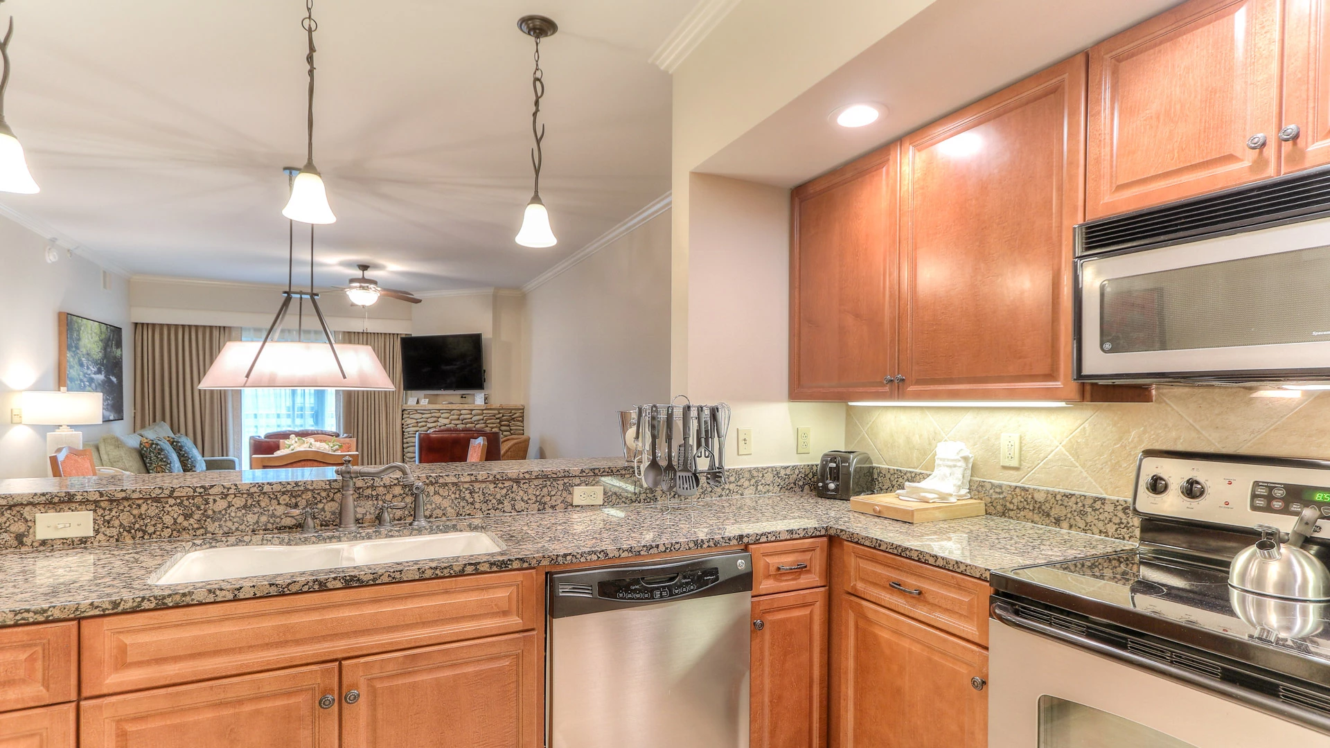 A kitchen with granite countertops, wood cabinets, and stainless steel appliances.