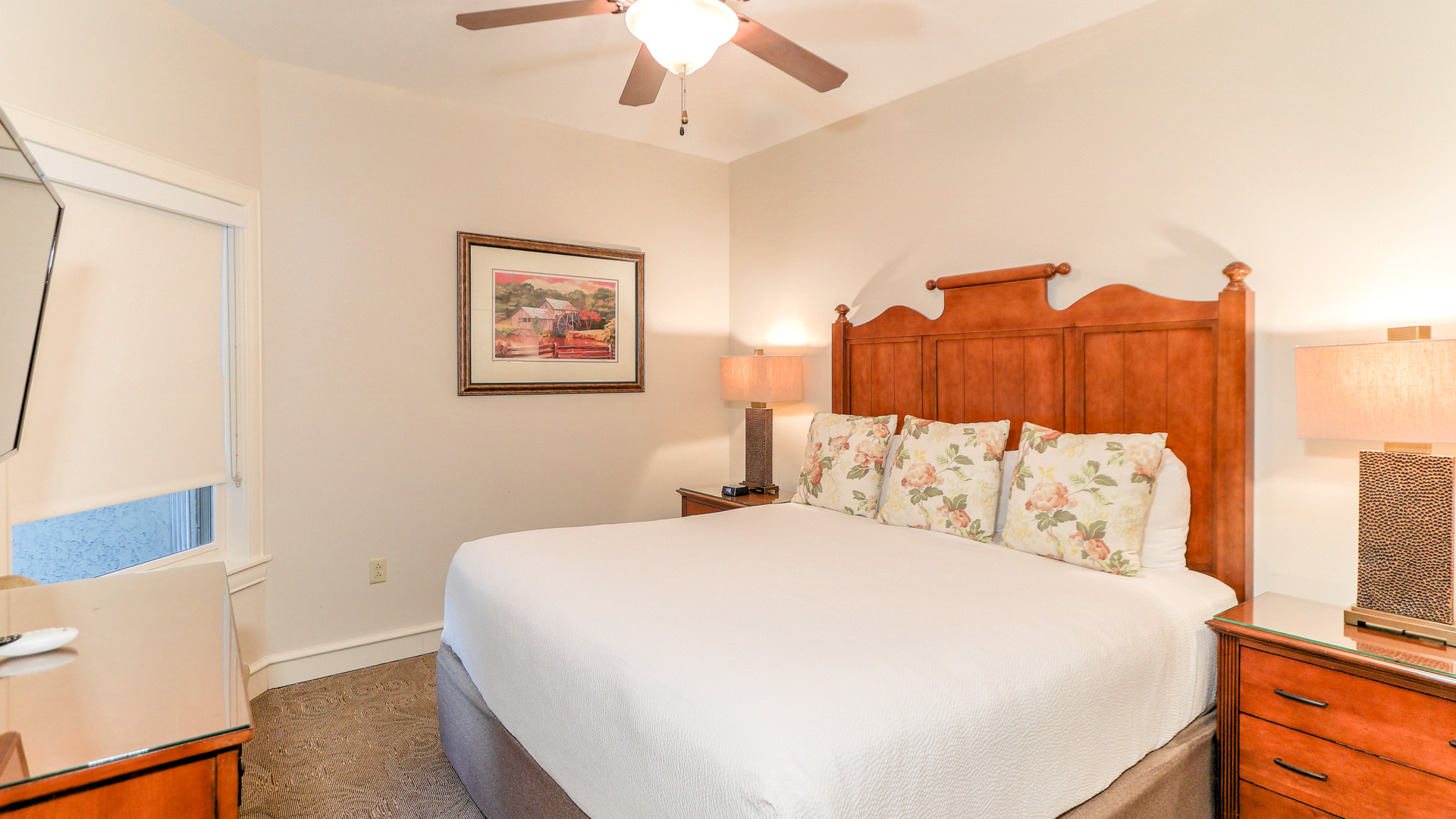 a bed with a fan and a picture on the wall