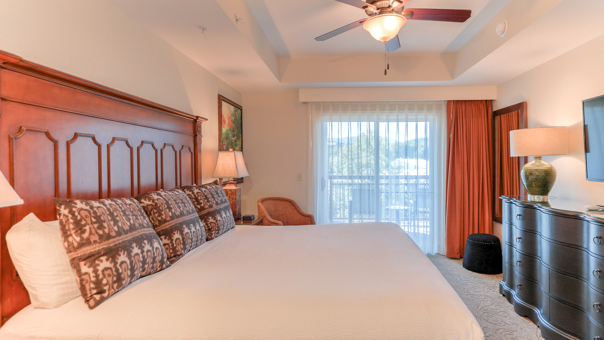 a bed with a ceiling fan and a chair in a room