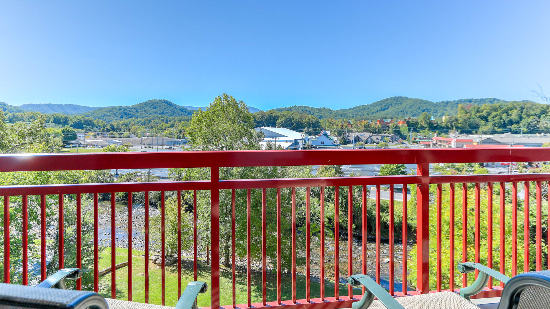 a red railing with trees and mountains in the background