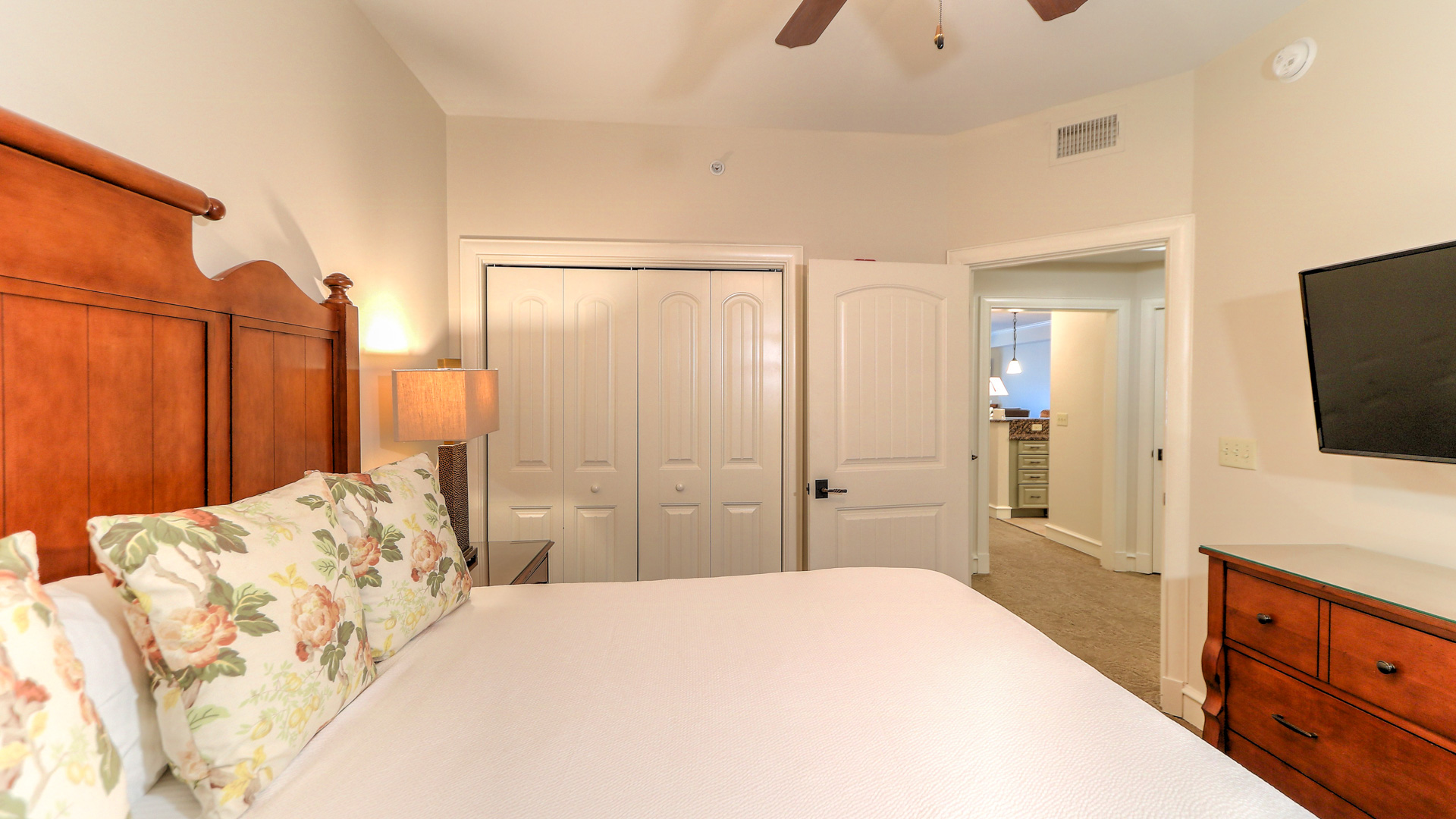 a bed with a floral pillow and a ceiling fan in a bedroom