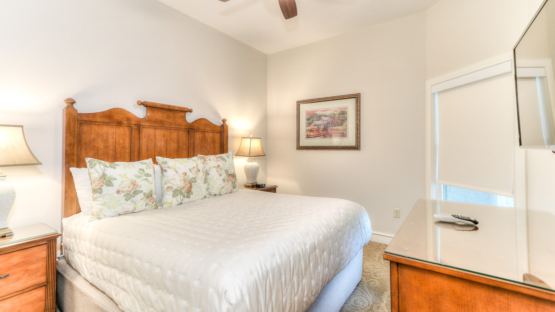a bed with a white bedding and a wooden table and a fan
