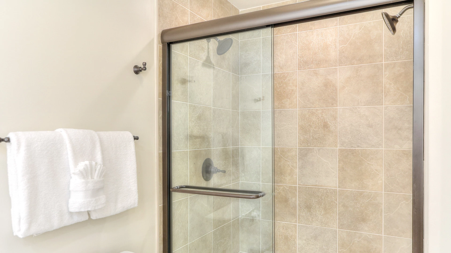 A bathroom shower with a glass door and tiled walls