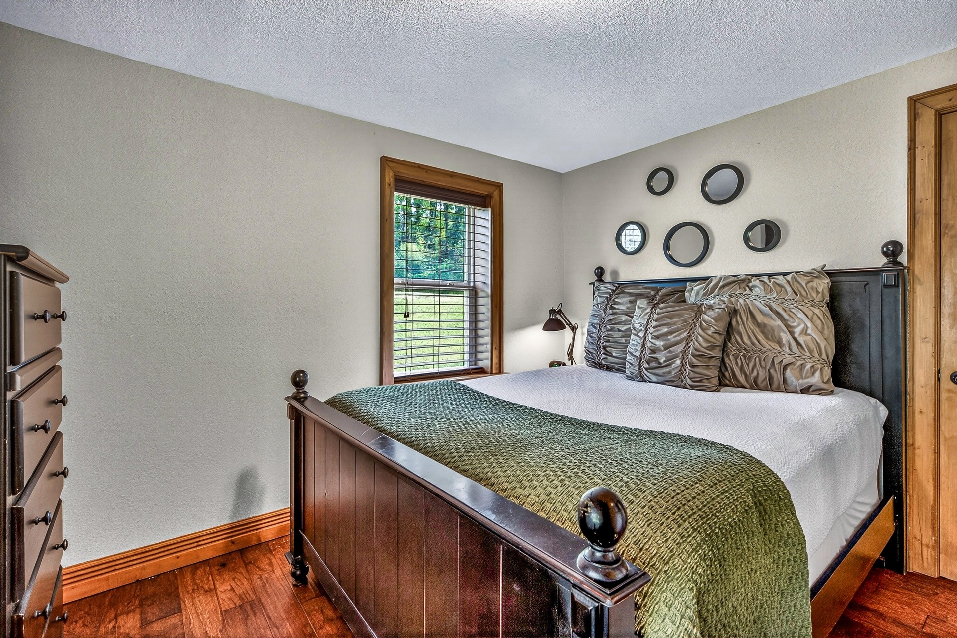 a bed with a green blanket and a lamp in a room