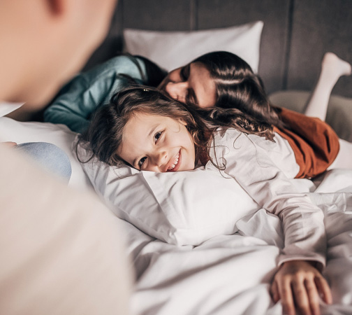 a woman and a girl lying on a bed