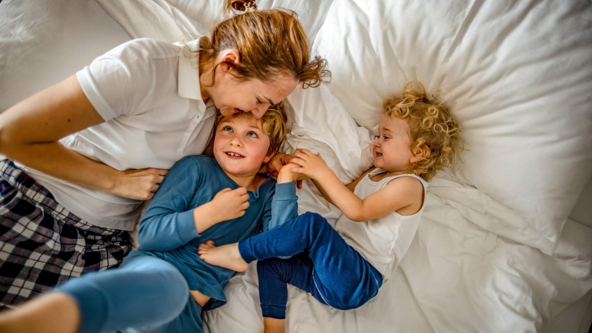 a woman and two children lying on a bed