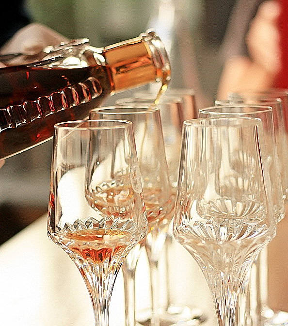 a person pouring liquid into a group of glasses