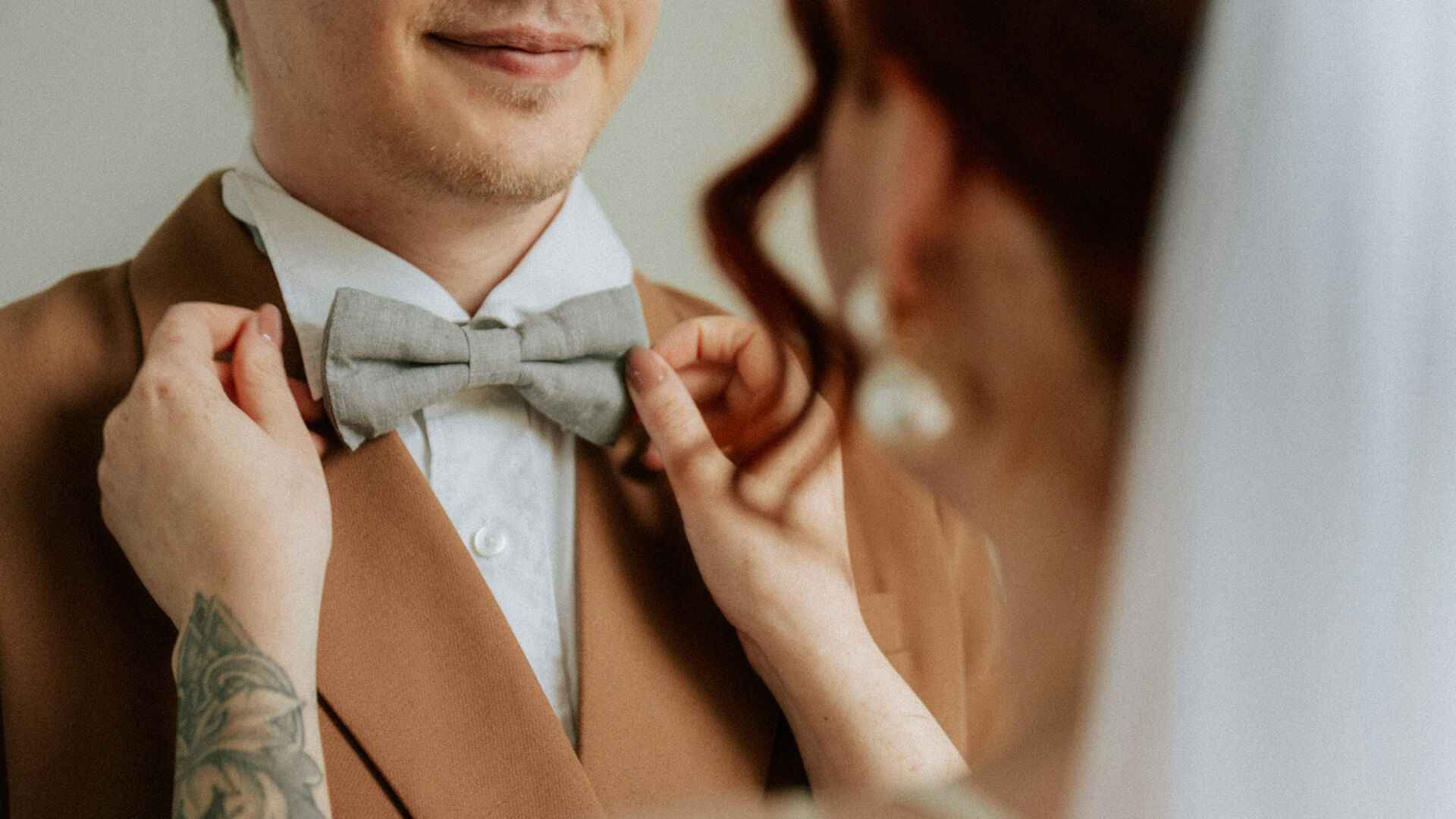 a woman adjusting a bow tie of a man