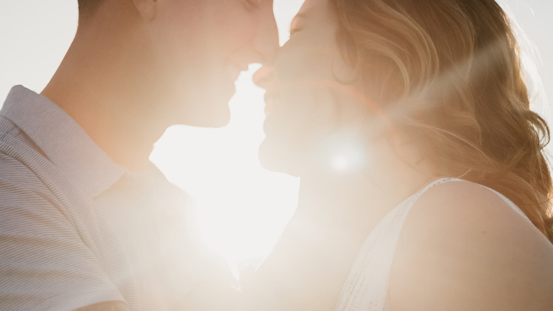 a man and woman smiling and touching noses