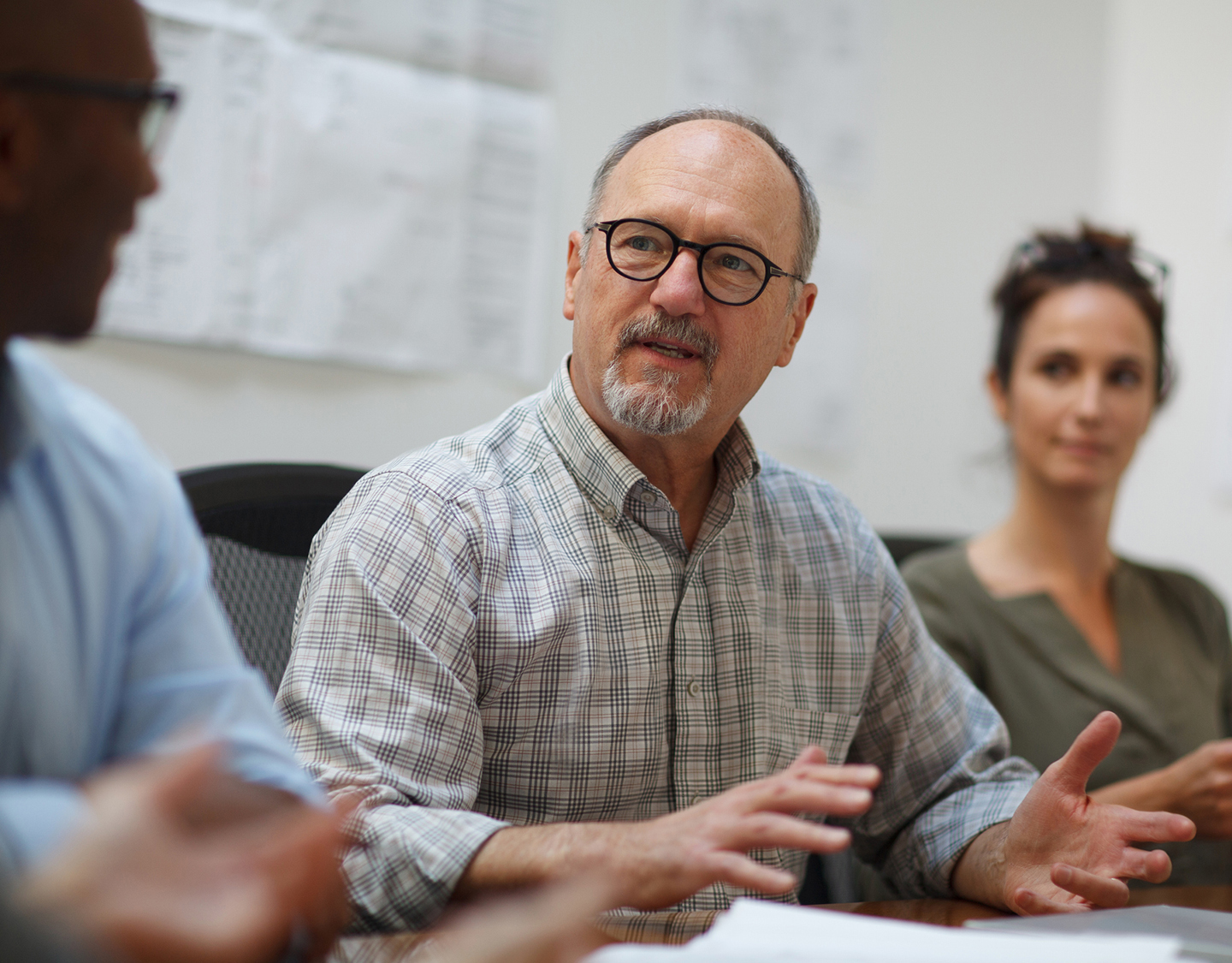 a man in glasses talking to a group of people