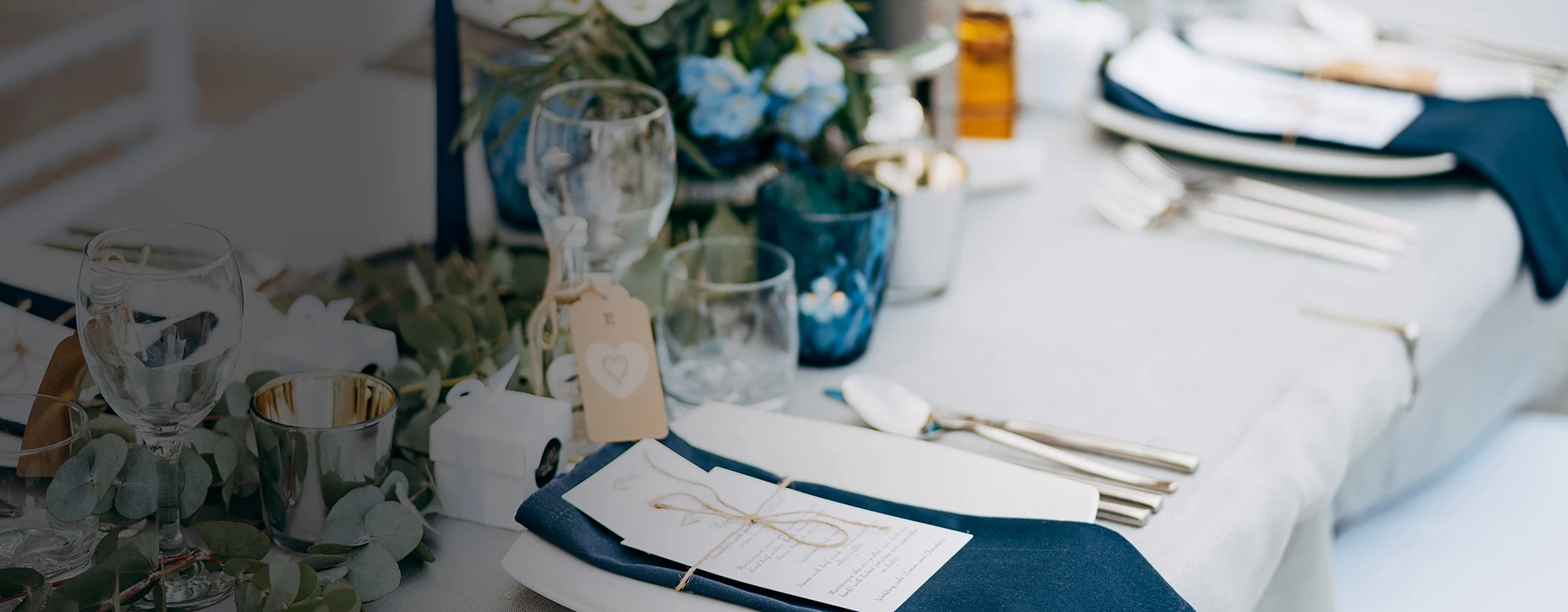 A formal table setting with white tablecloth, blue napkins, and elegant dinnerware.