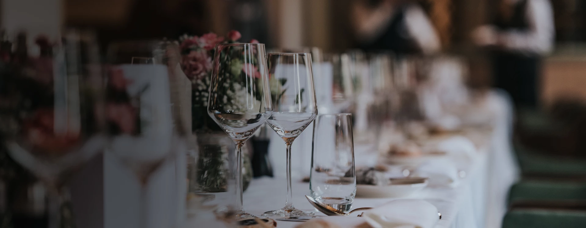 A formal dining table set with wine glasses, flowers, and fine china.