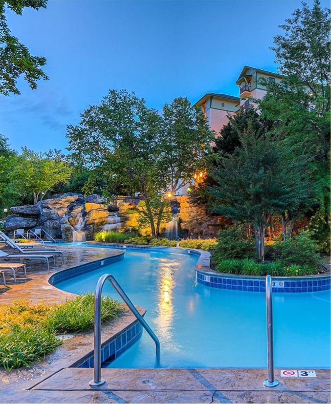 a pool with a waterfall and trees