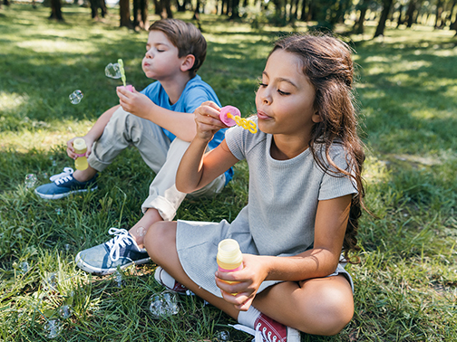 a boy and girl blowing bubbles