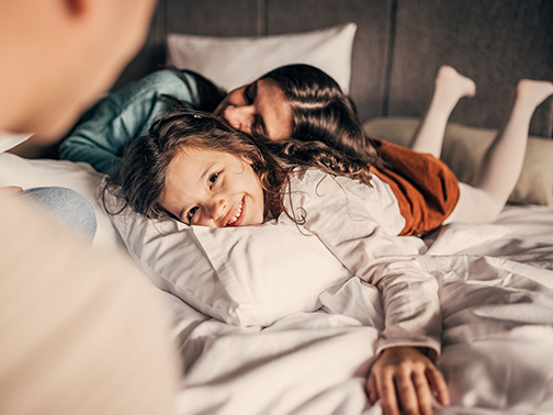 a woman and a girl lying on a bed
