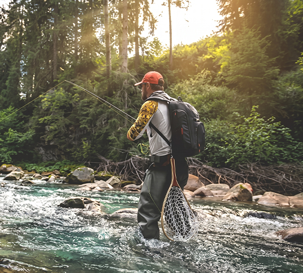 a man standing in a river with a net and a fishing pole