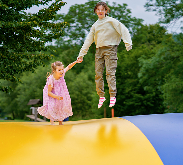a boy and girl jumping on a trampoline