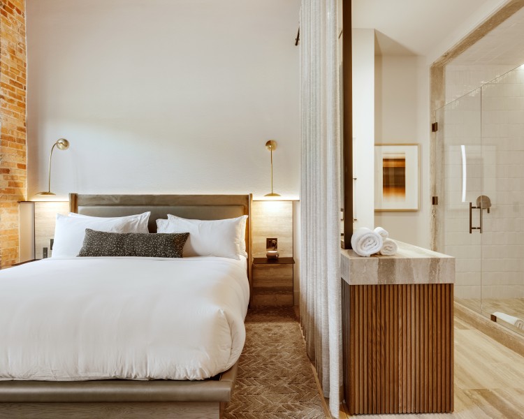 a bed with white sheets and pillows in a hotel room