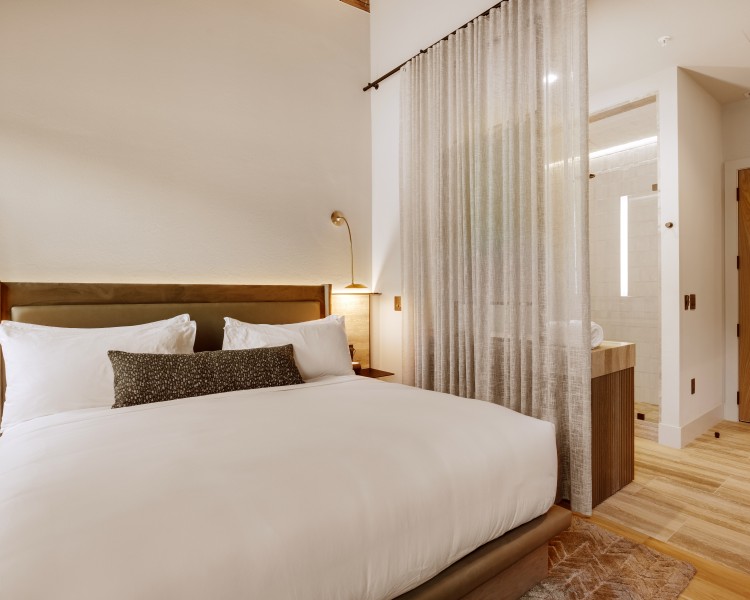 a bed with white sheets and pillows in a room
