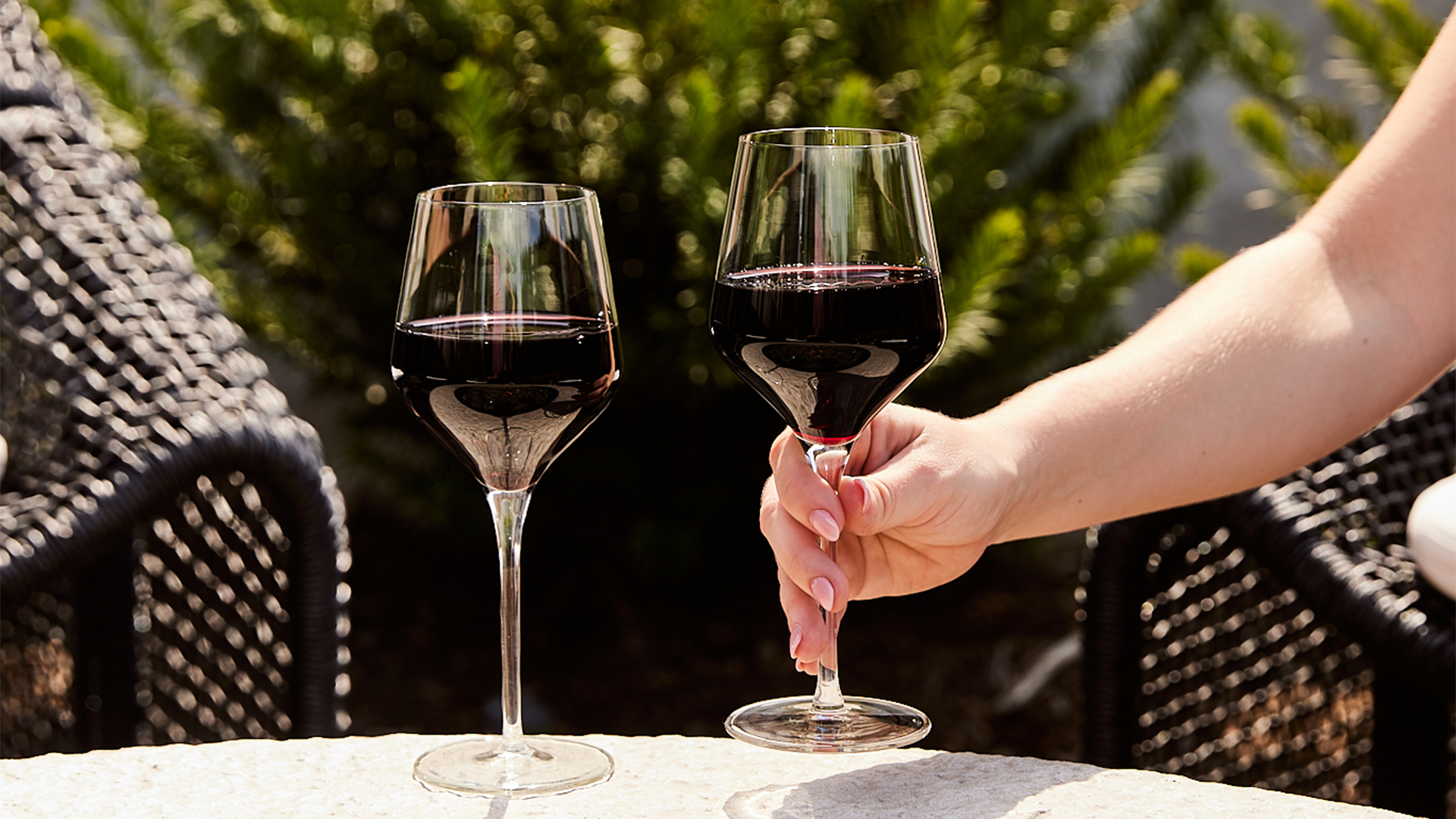 a hand holding wine glasses