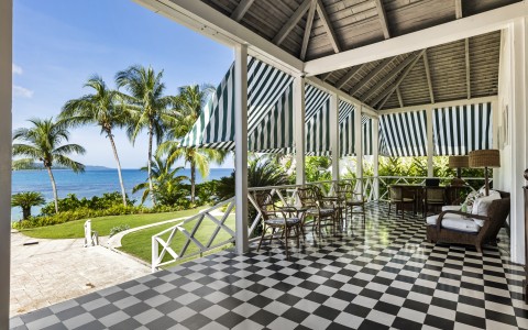 a covered patio with a black and white checkered floor and chairs