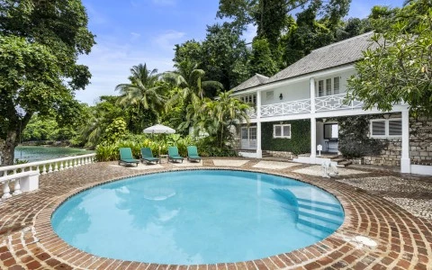 a pool with chairs in front of a house