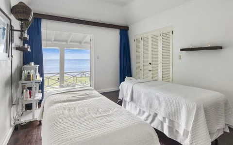 two beds in a room with a view of the ocean