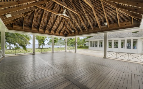 a large wooden patio with a large ceiling fan and a large building