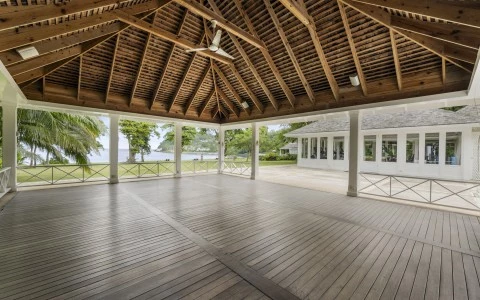 a large wooden patio with a large ceiling fan and a large building