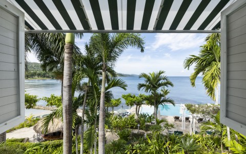 a view of a beach from a roof over a palm tree