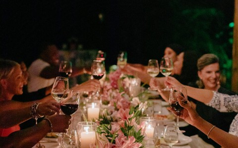 a group of people holding wine glasses at a dinner table