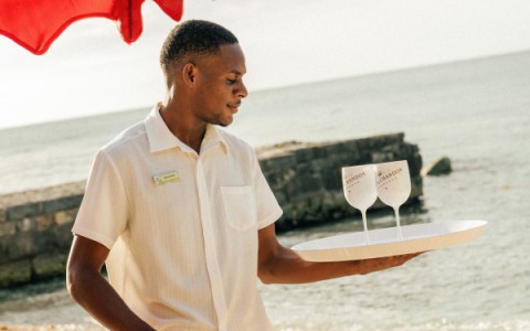 a man holding a tray with two glasses on it