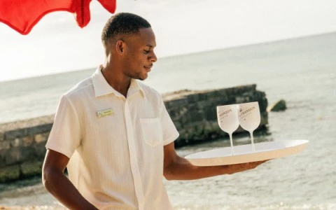a man holding a tray with two glasses on it