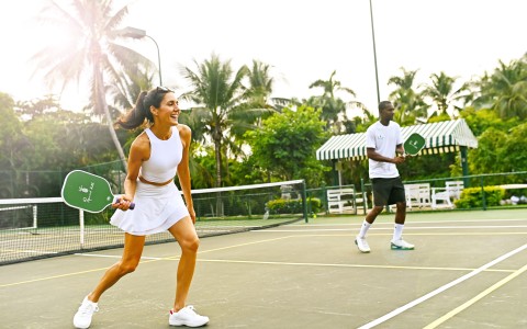 a man and woman holding tennis rackets on a tennis court