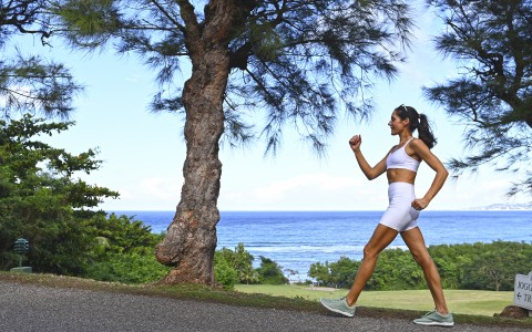 a woman running on a path near a tree