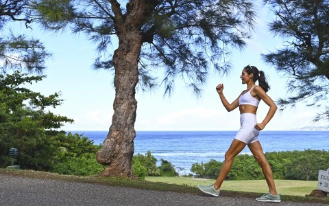 a woman running on a path near a tree