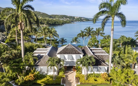 a house with palm trees and a body of water