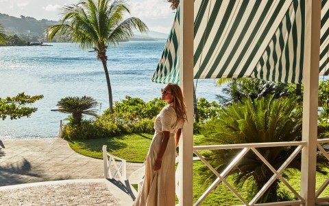 a woman standing on a porch by a body of water