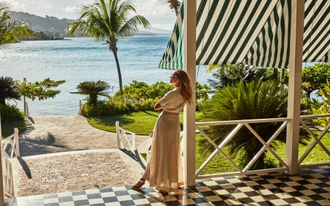a woman standing on a porch by a body of water