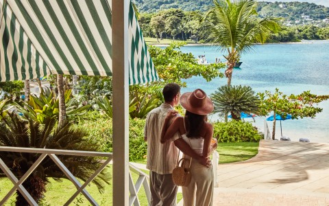 a man and woman standing on a porch looking at a body of water