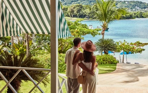 a man and woman standing on a porch looking at a body of water