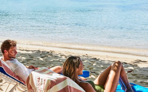 a man and woman lying on chairs on a beach