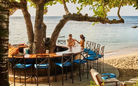 people standing around a bar on a beach